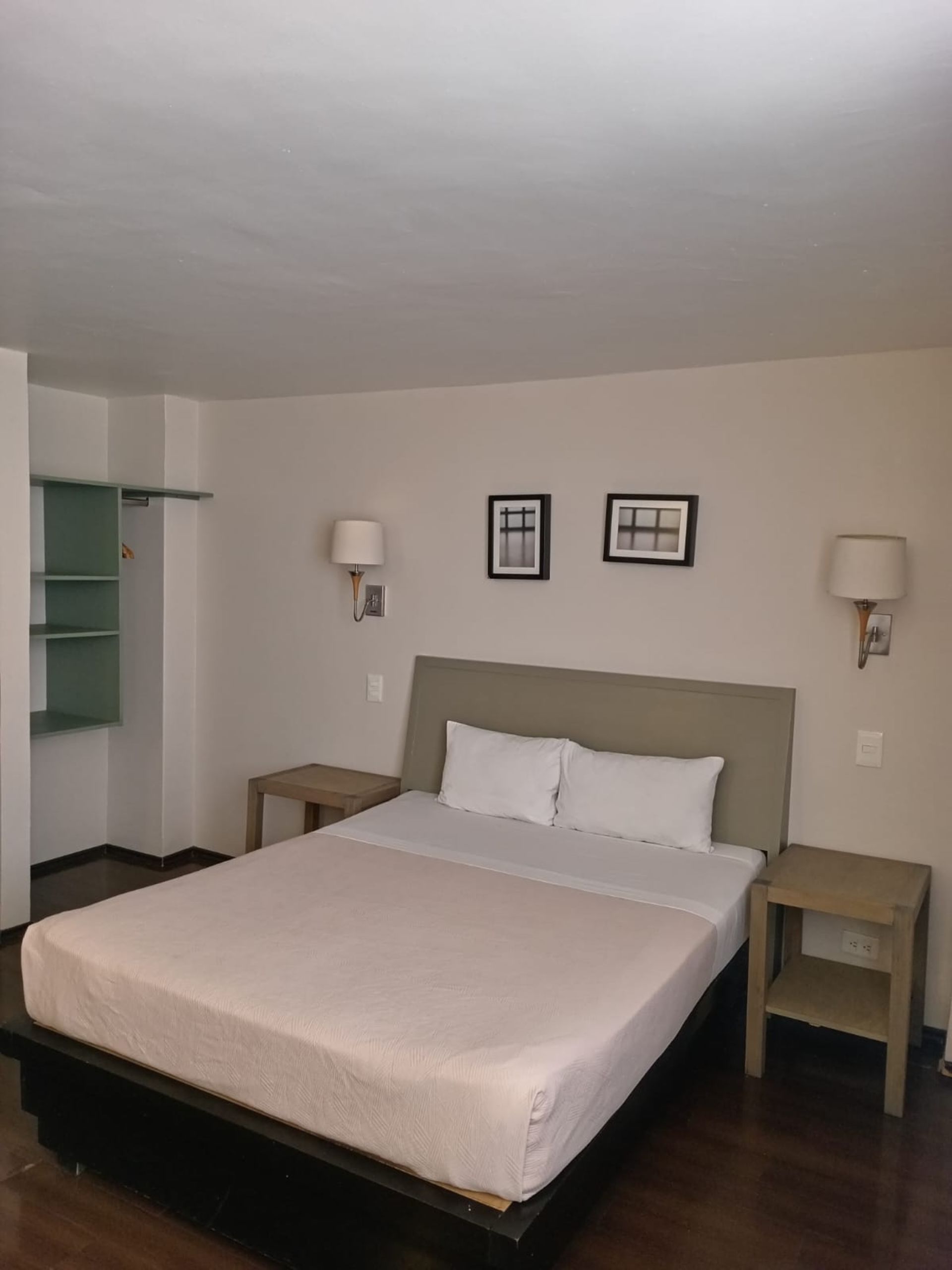 Bedroom with a bed, nightstand, and a patterned wallpaper accent wall, reflected in a framed mirror.