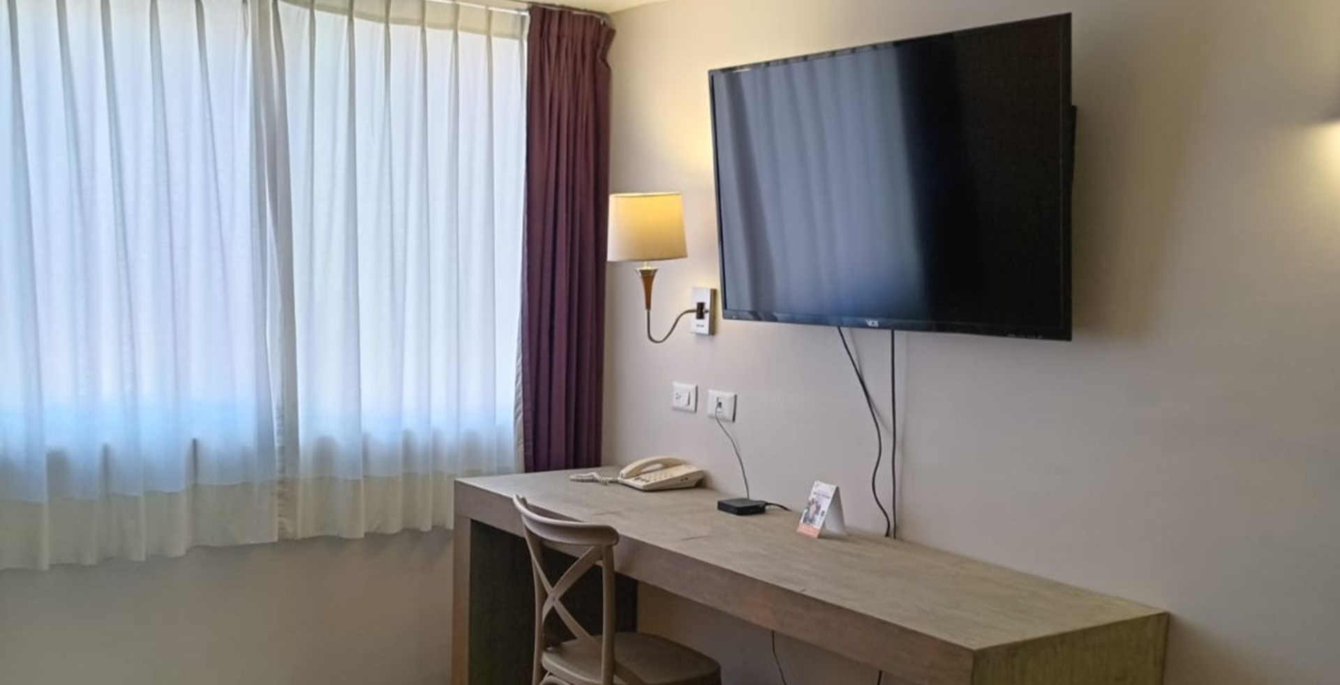 Man standing on a rock, silhouetted against a sunrise with a bright sunburst.