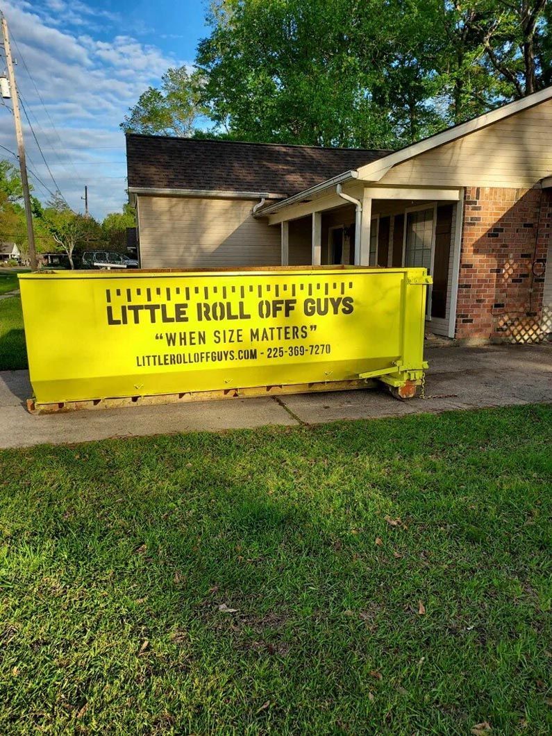 A yellow dumpster is parked in front of a house.