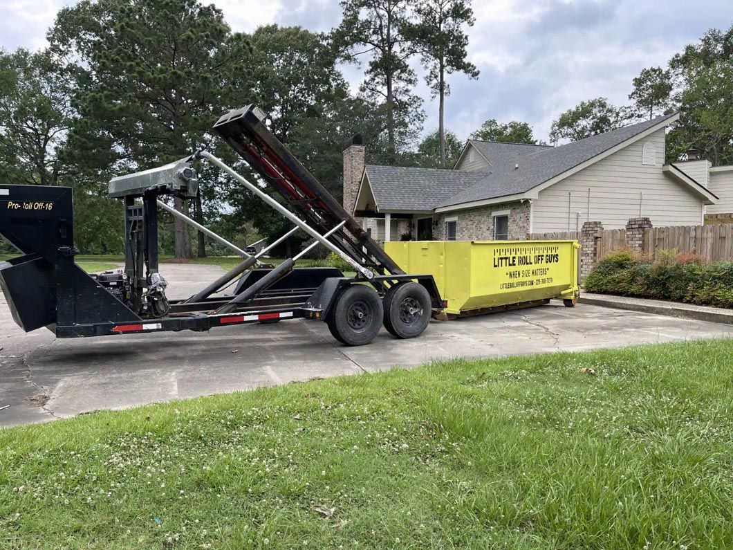 A dumpster on a trailer is parked in front of a house.