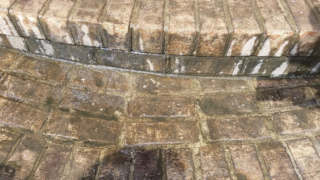 Close-up of weathered, stained brick stairs and a brick patio, showing signs of dirt and uneven wear.