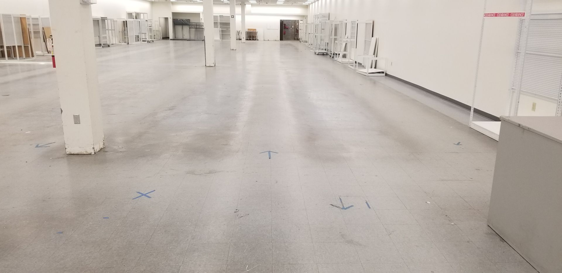 Empty industrial space with concrete floor, white walls and support pillars.