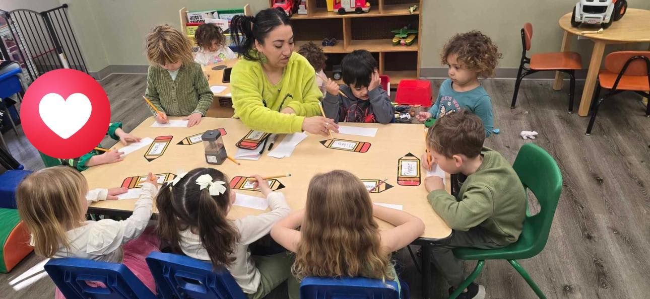 Children and a teacher at a table in a classroom, working on a project.