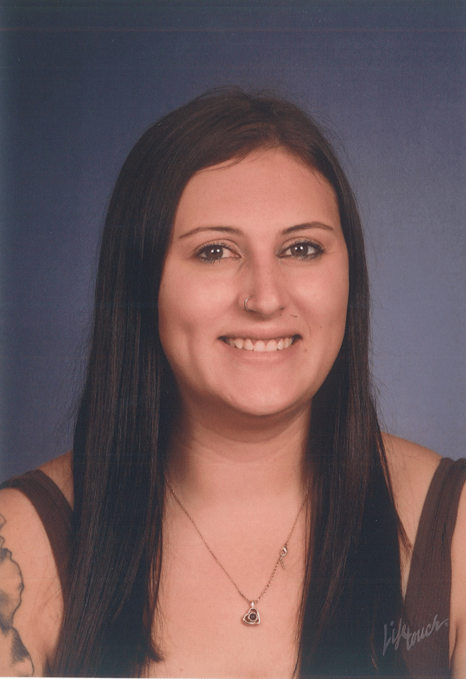 Woman with long dark hair, wearing a necklace, smiling.