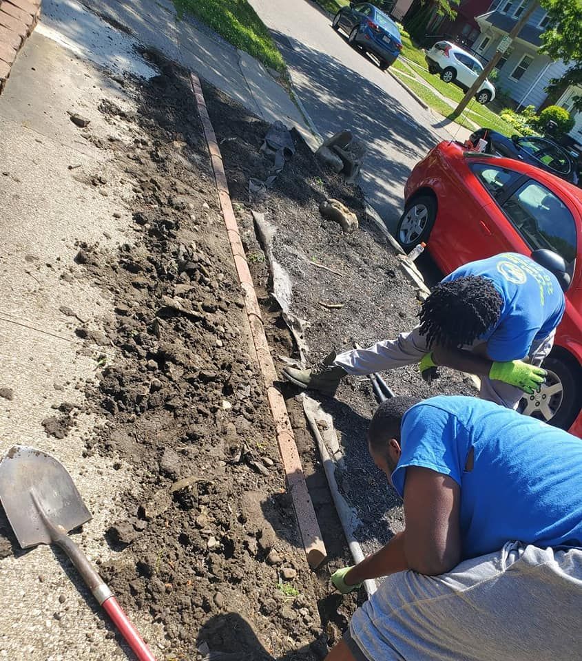 Two men are digging in the dirt on the side of the road.