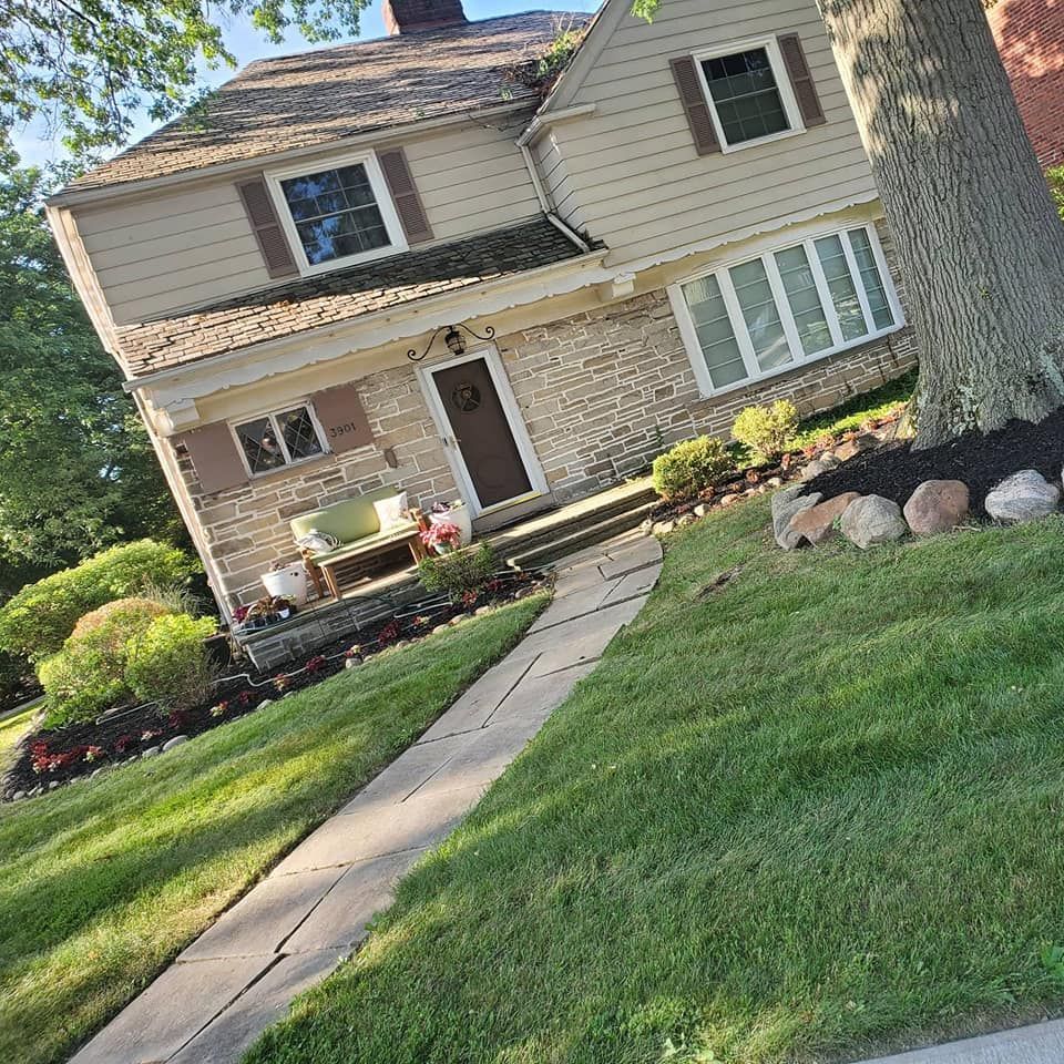 A house with a walkway leading to it and a tree in front of it.