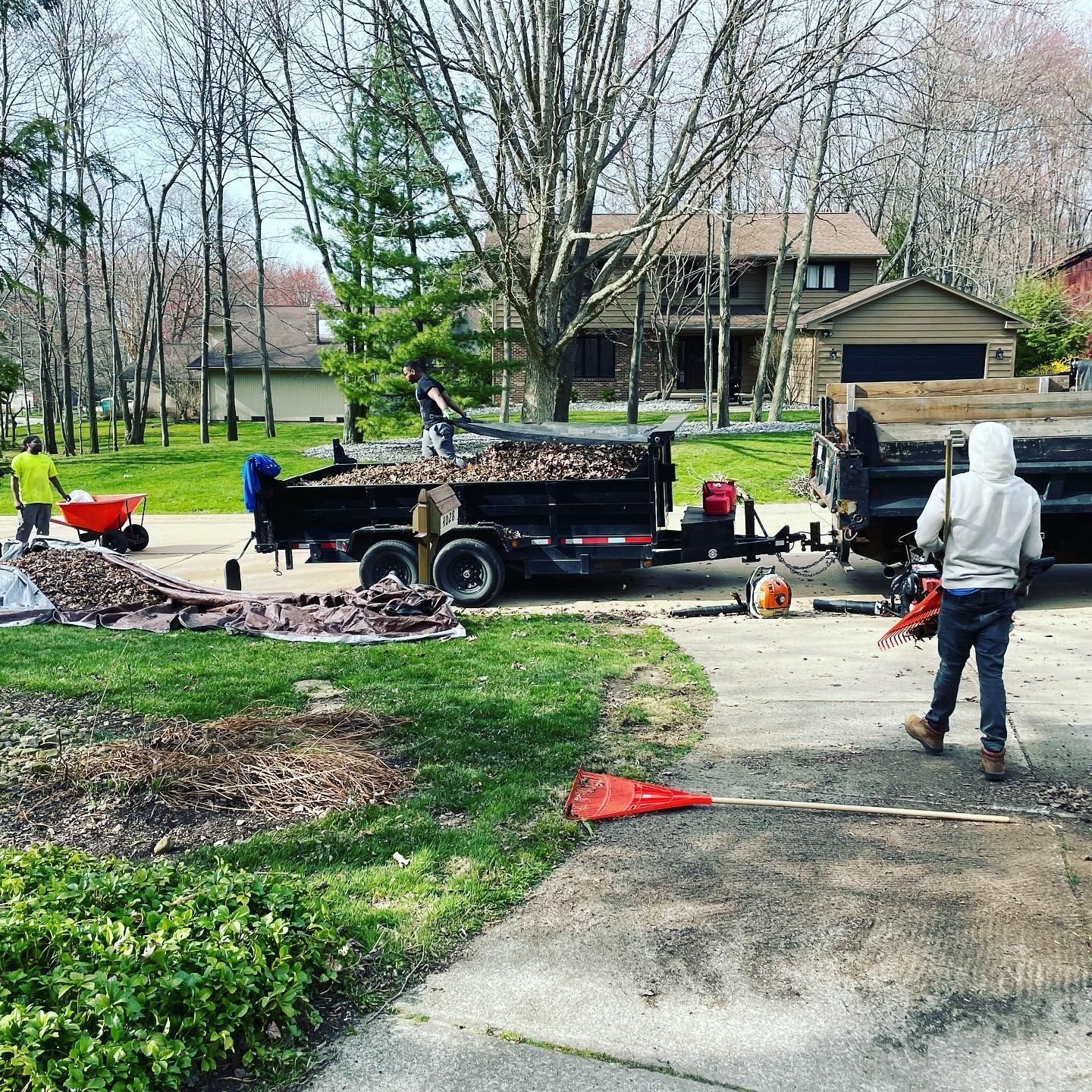 A man is standing in front of a dump truck in a driveway.