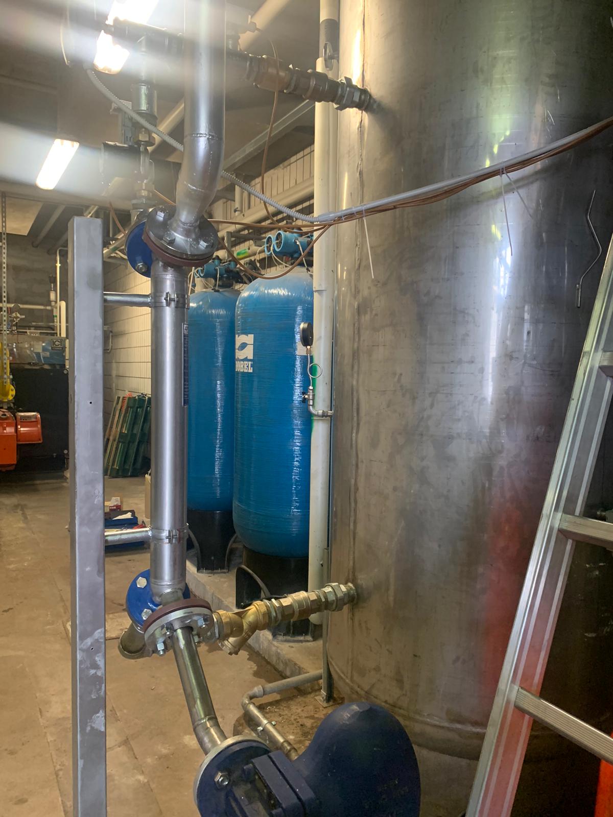 Una scala è appoggiata accanto a un serbatoio di acciaio inossidabile in una fabbrica.