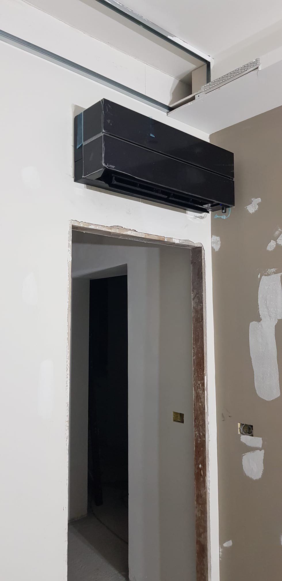 In una stanza è appeso al soffitto un condizionatore nero.