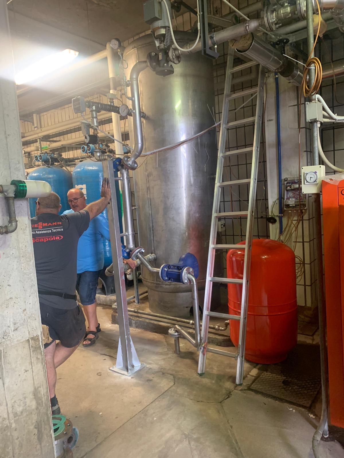 Un uomo è in piedi in una stanza con dei tubi e una scala.