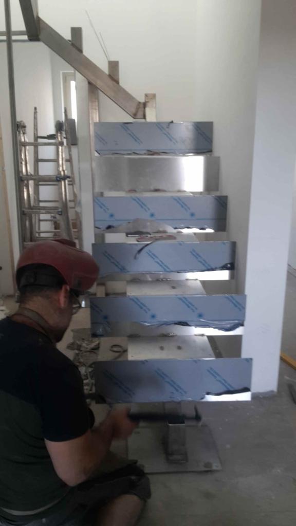 Un uomo sta lavorando su una scala in acciaio inossidabile.