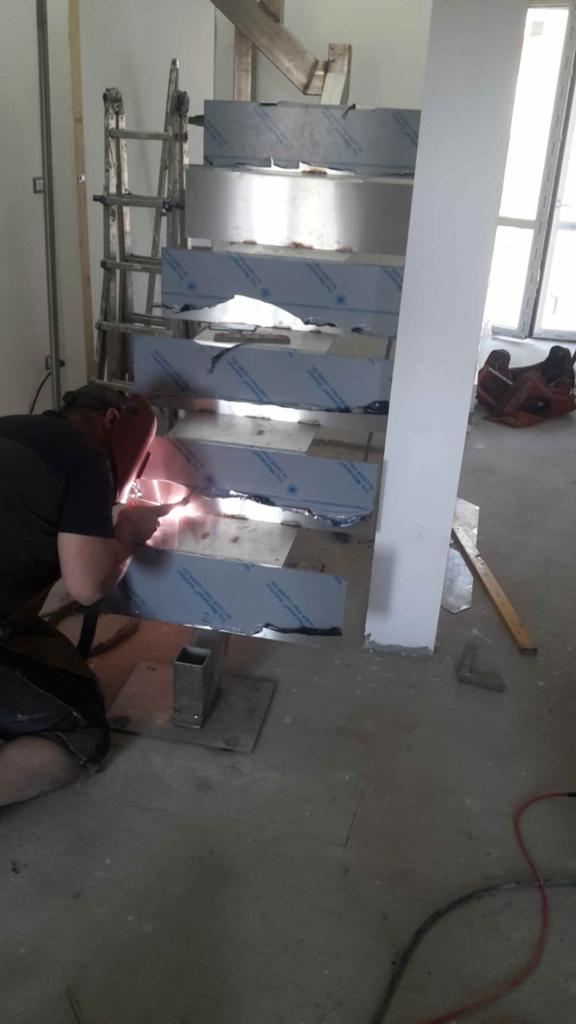 Un uomo sta saldando una scala in acciaio inossidabile in una stanza.