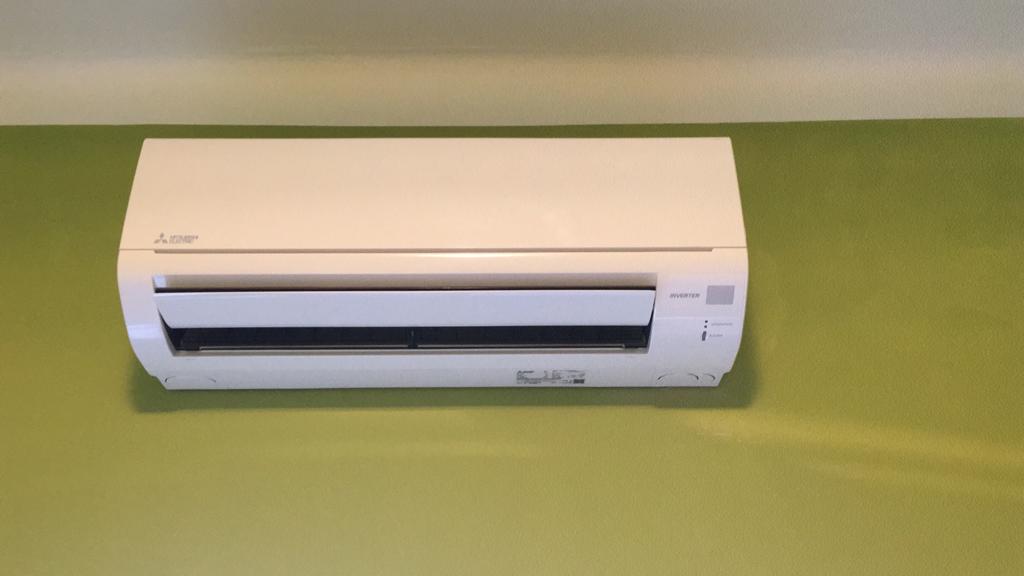 Un condizionatore bianco è appeso a una parete verde.