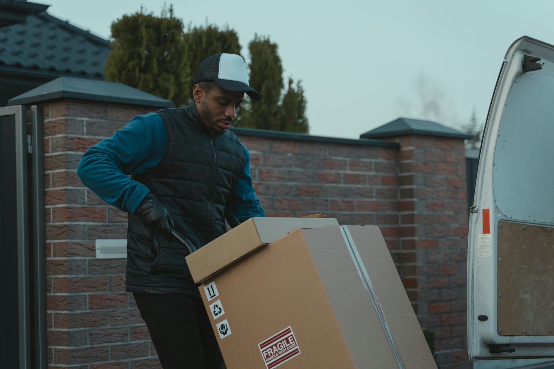 A delivery man is loading a cardboard box into a van.