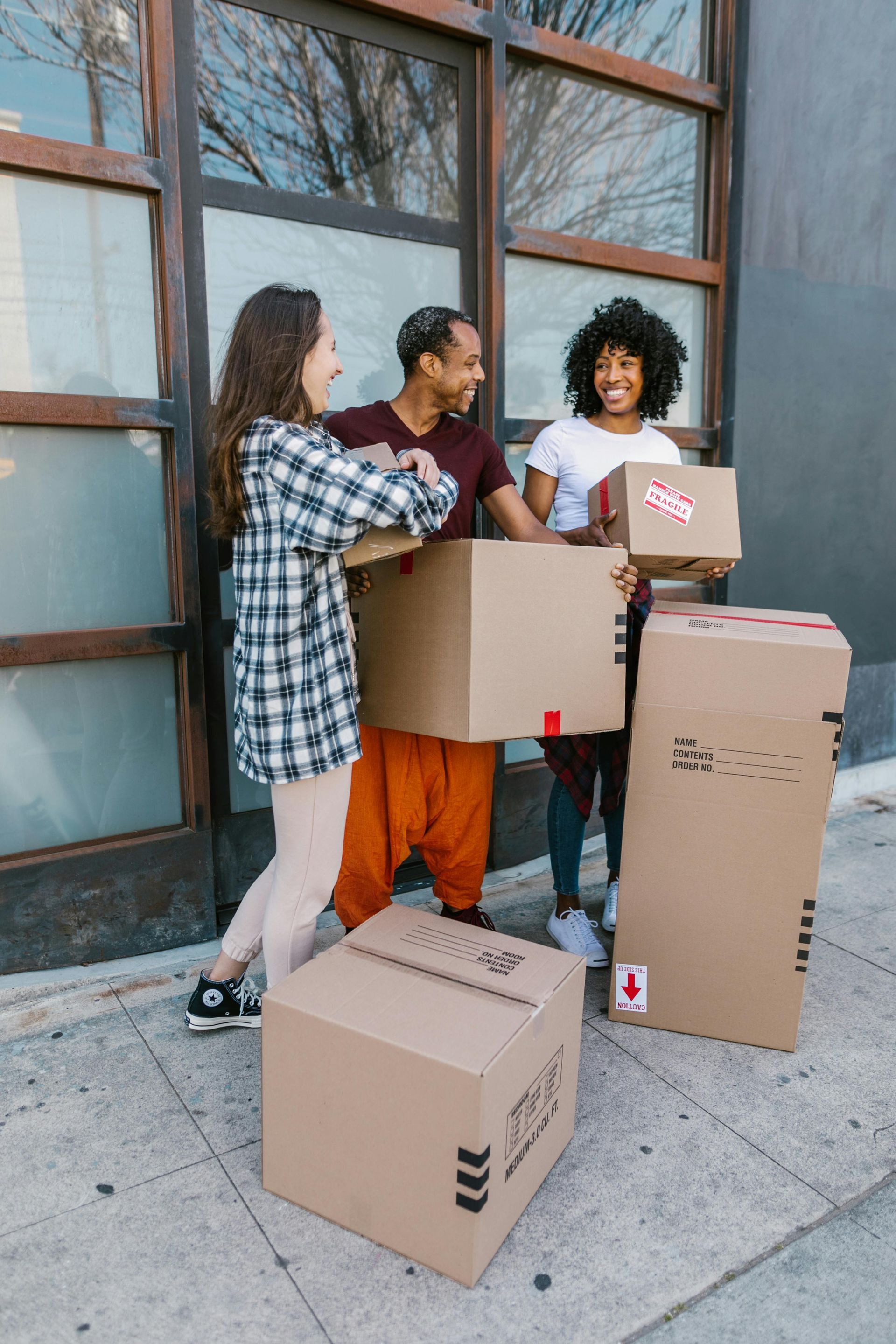 A group of people are carrying cardboard boxes on a sidewalk.