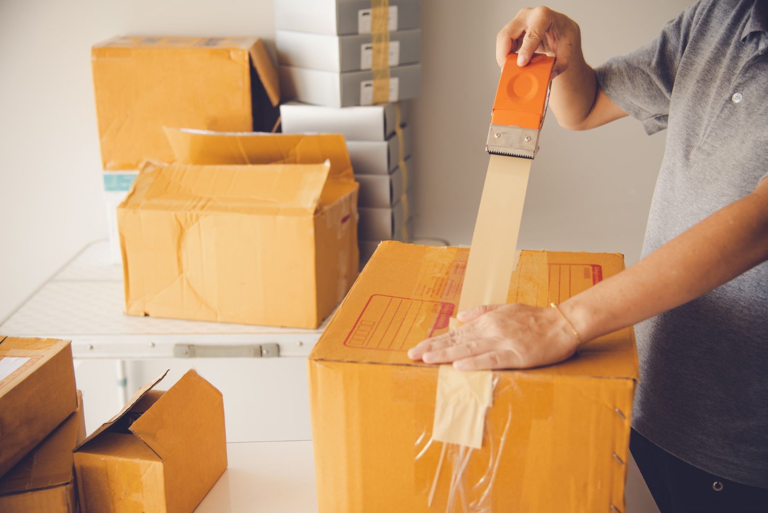 A person is wrapping a cardboard box with tape.