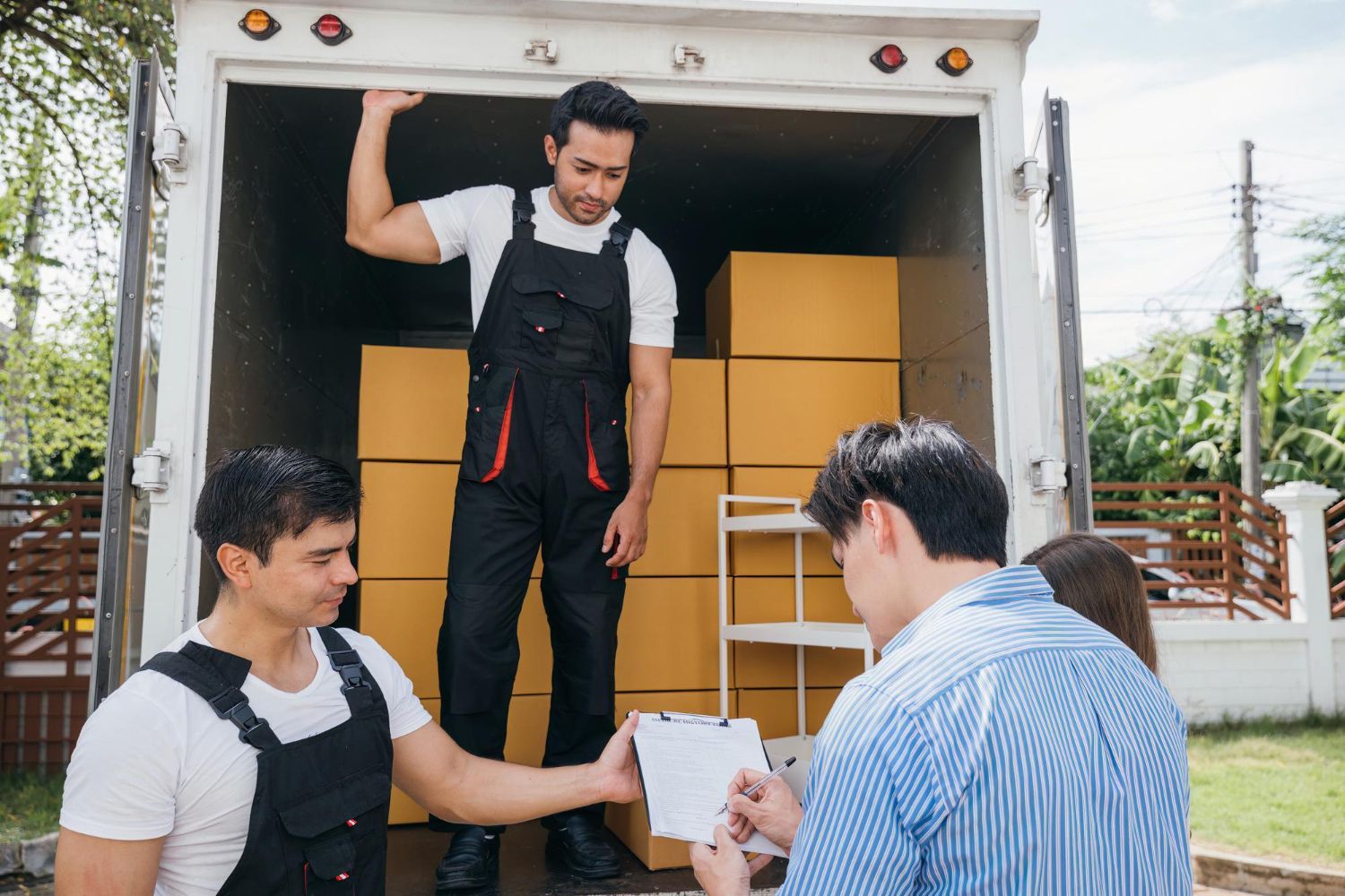 A group of men are standing in front of a truck filled with boxes.