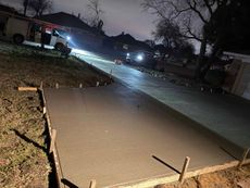 A concrete driveway is being built at night.