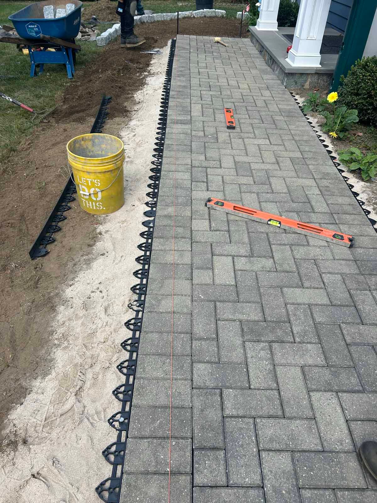 A brick walkway is being built in front of a house.