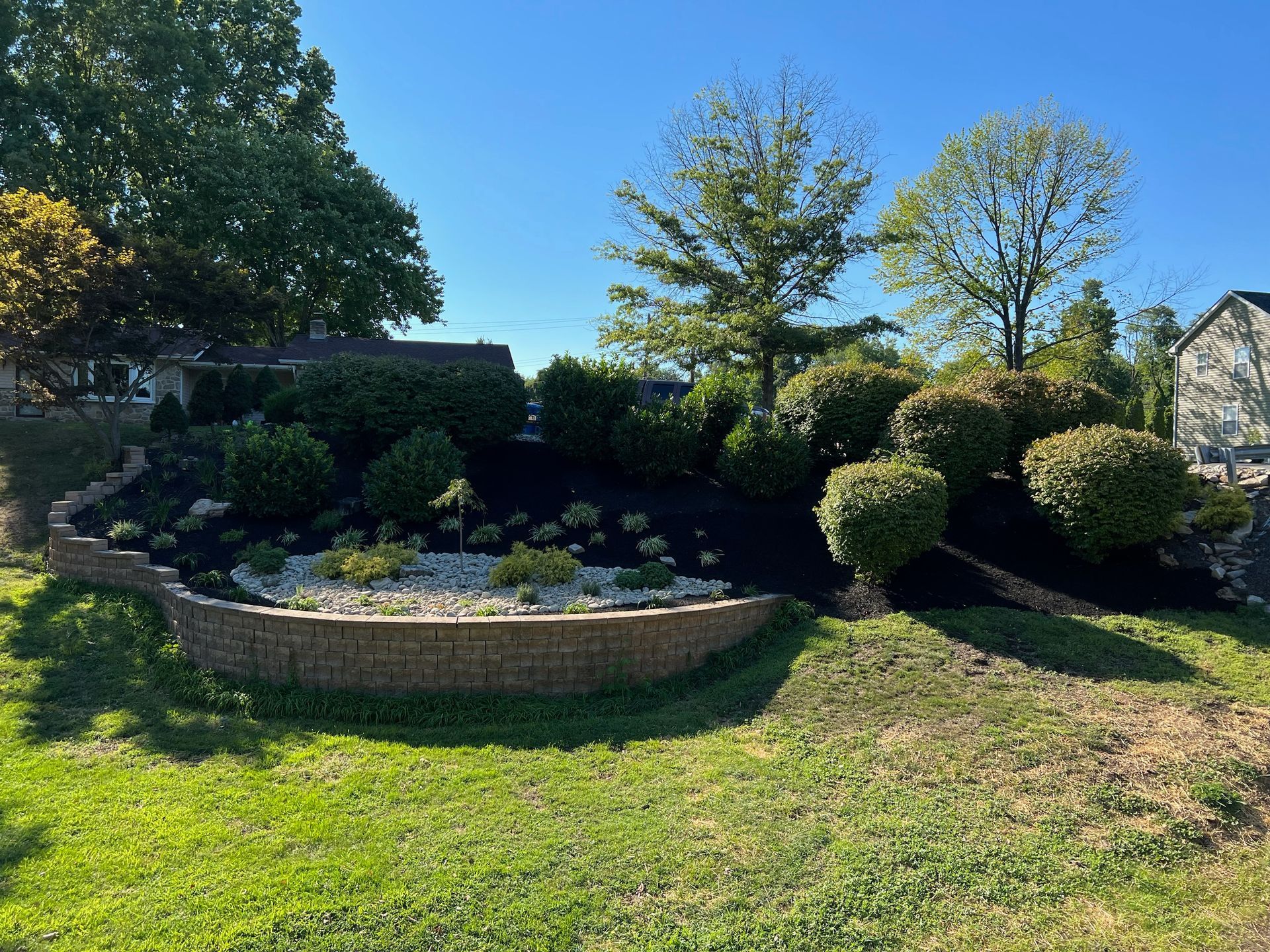 A Lush Green Yard with a Brick Wall Surrounded by Bushes and Trees — Langhorne, PA — Cappuccino Land Services