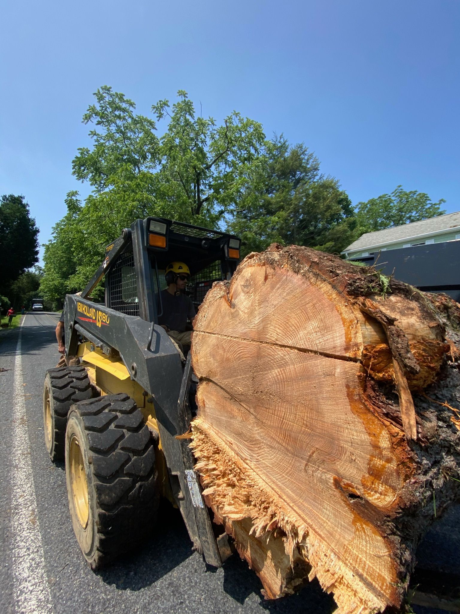 A bulldozer is carrying a large log down a road.