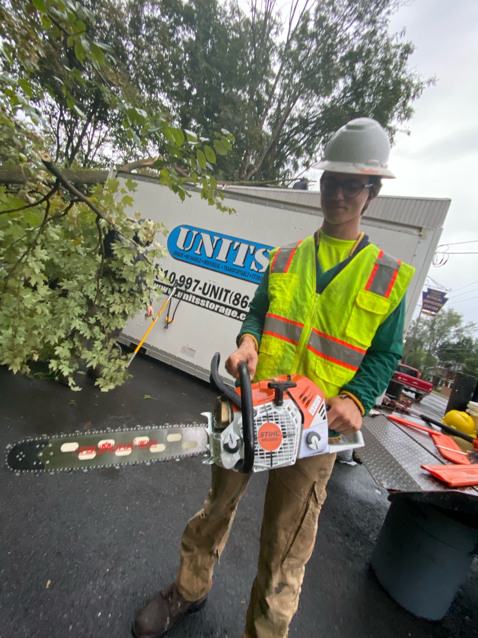 A man is holding a chainsaw in front of a units truck