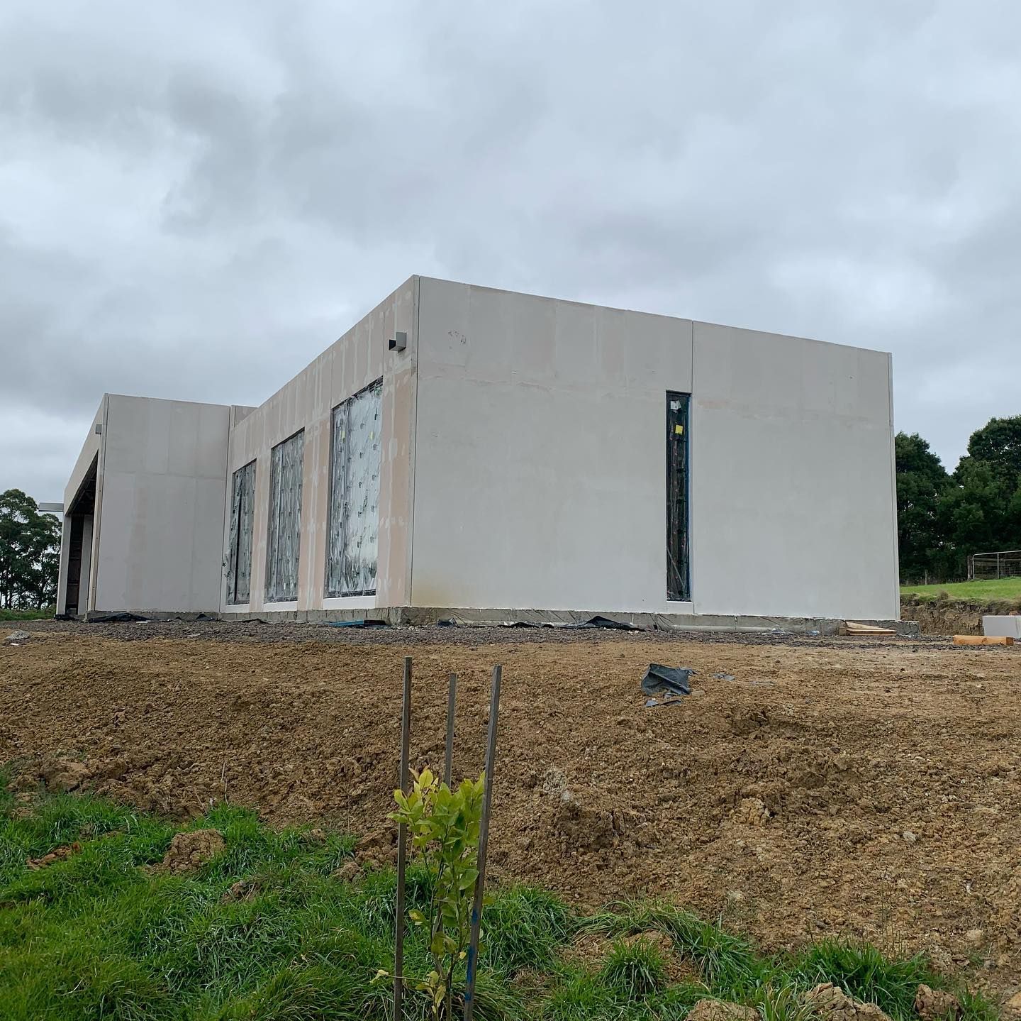 A large white building is sitting in the middle of a dirt field.