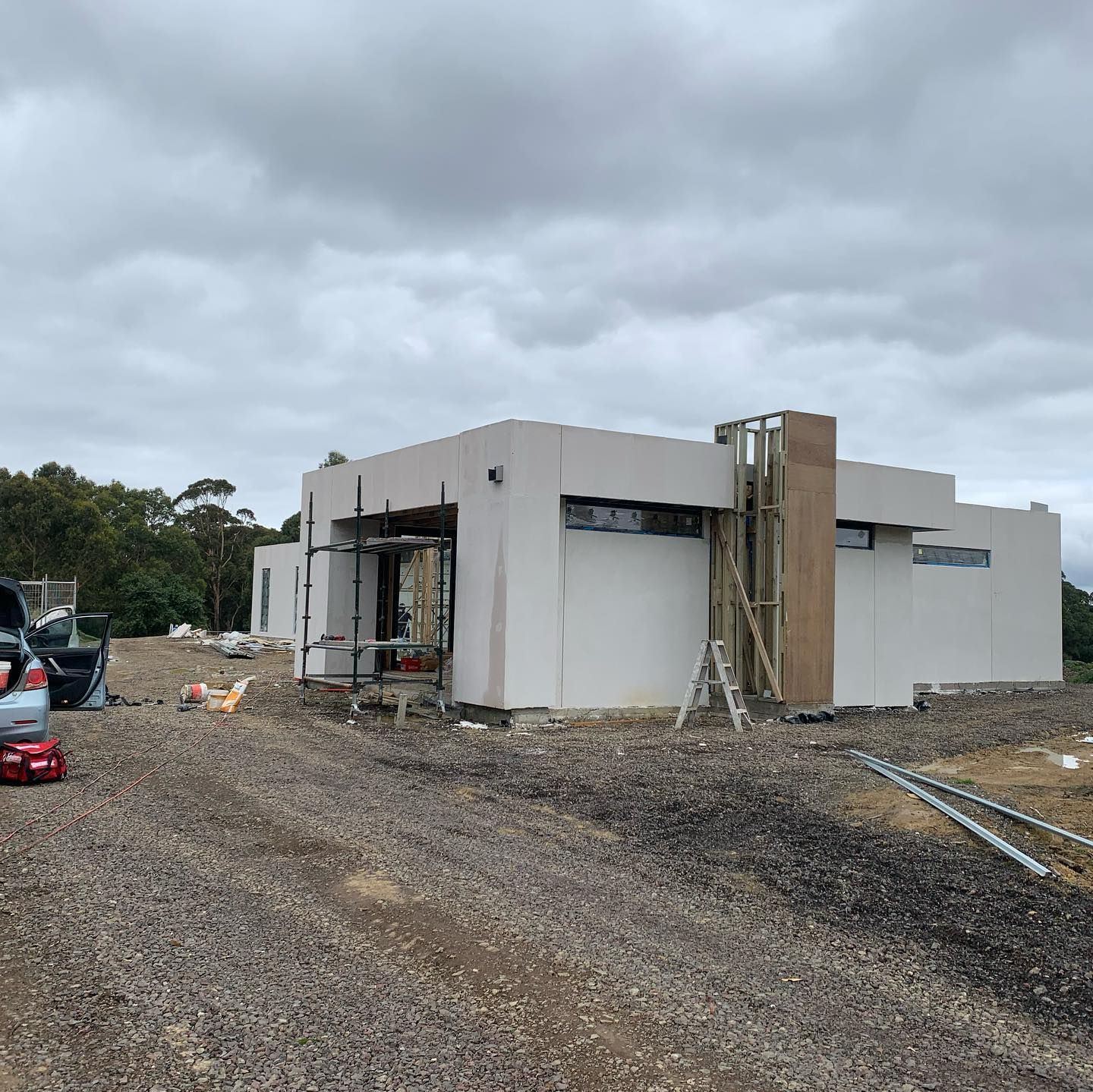 A white house is being built in a dirt field.