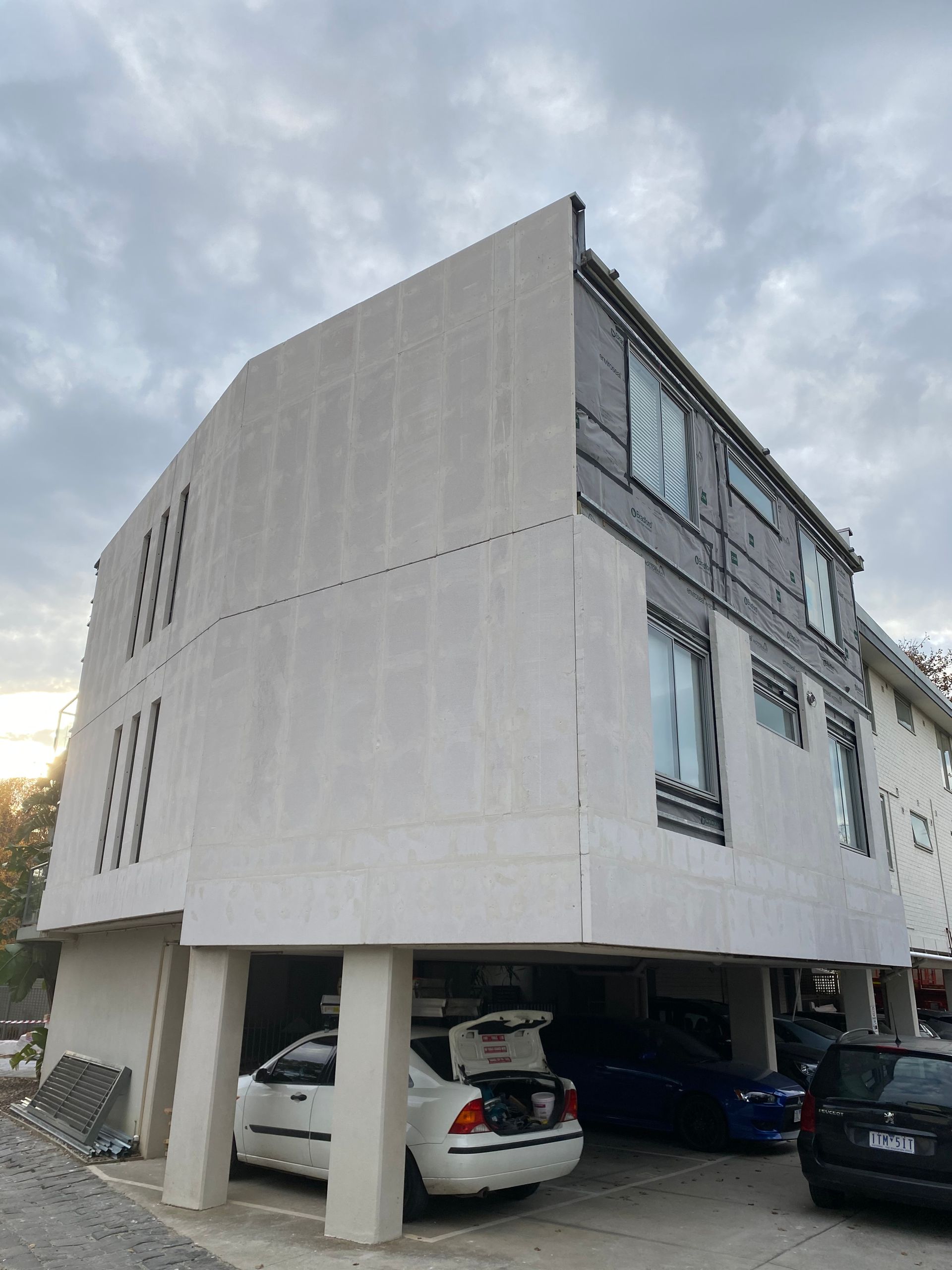 A white car is parked in front of a large building