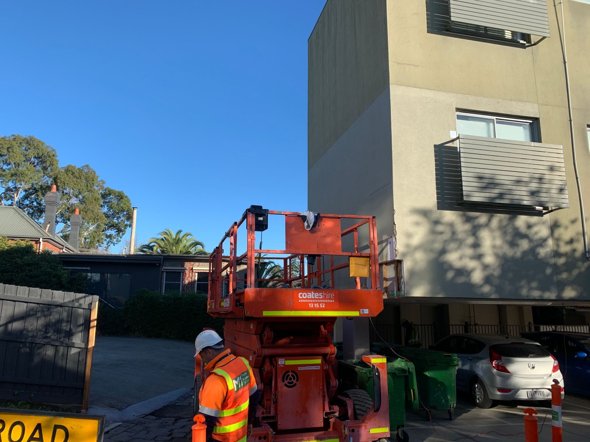 A man is standing on a lift in front of a building.