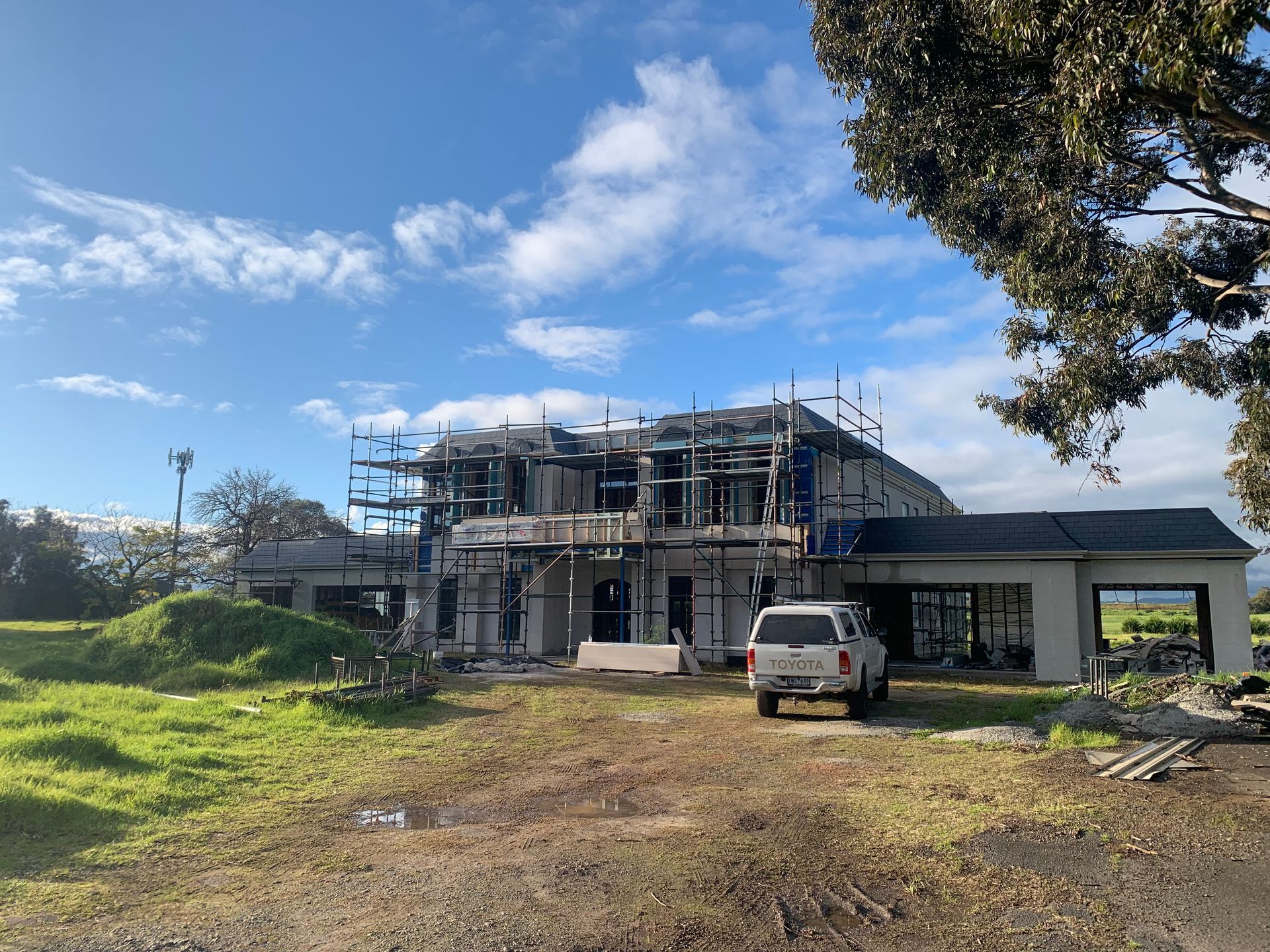 A white truck is parked in front of a house under construction.