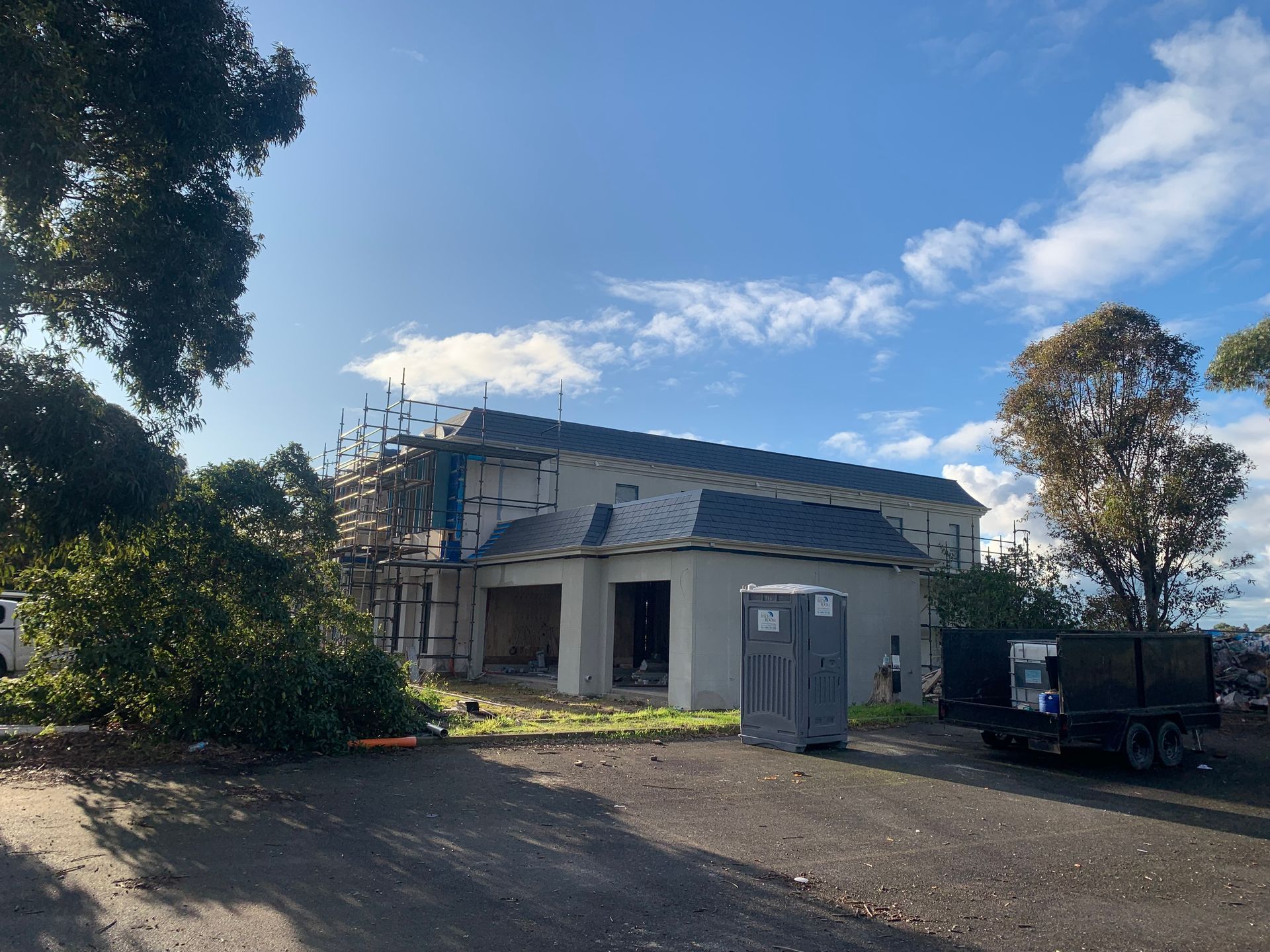 A large white house is being built with scaffolding and a truck parked in front of it.