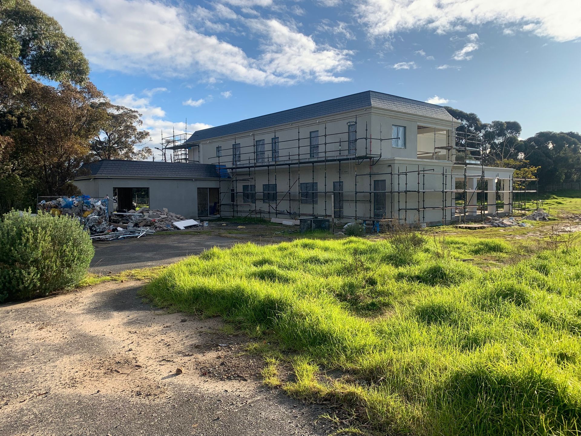 A large house is being built in a grassy field.