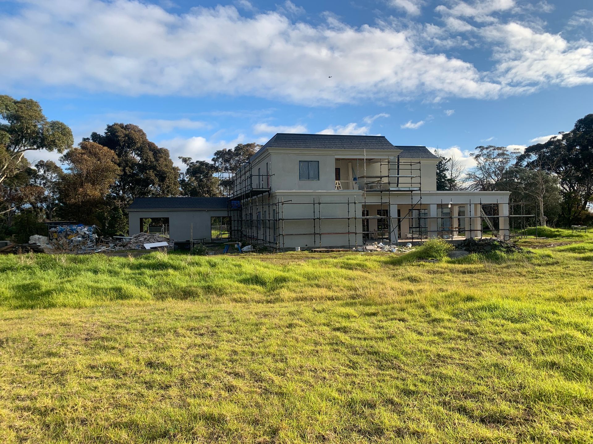 A large house is being built in a grassy field.