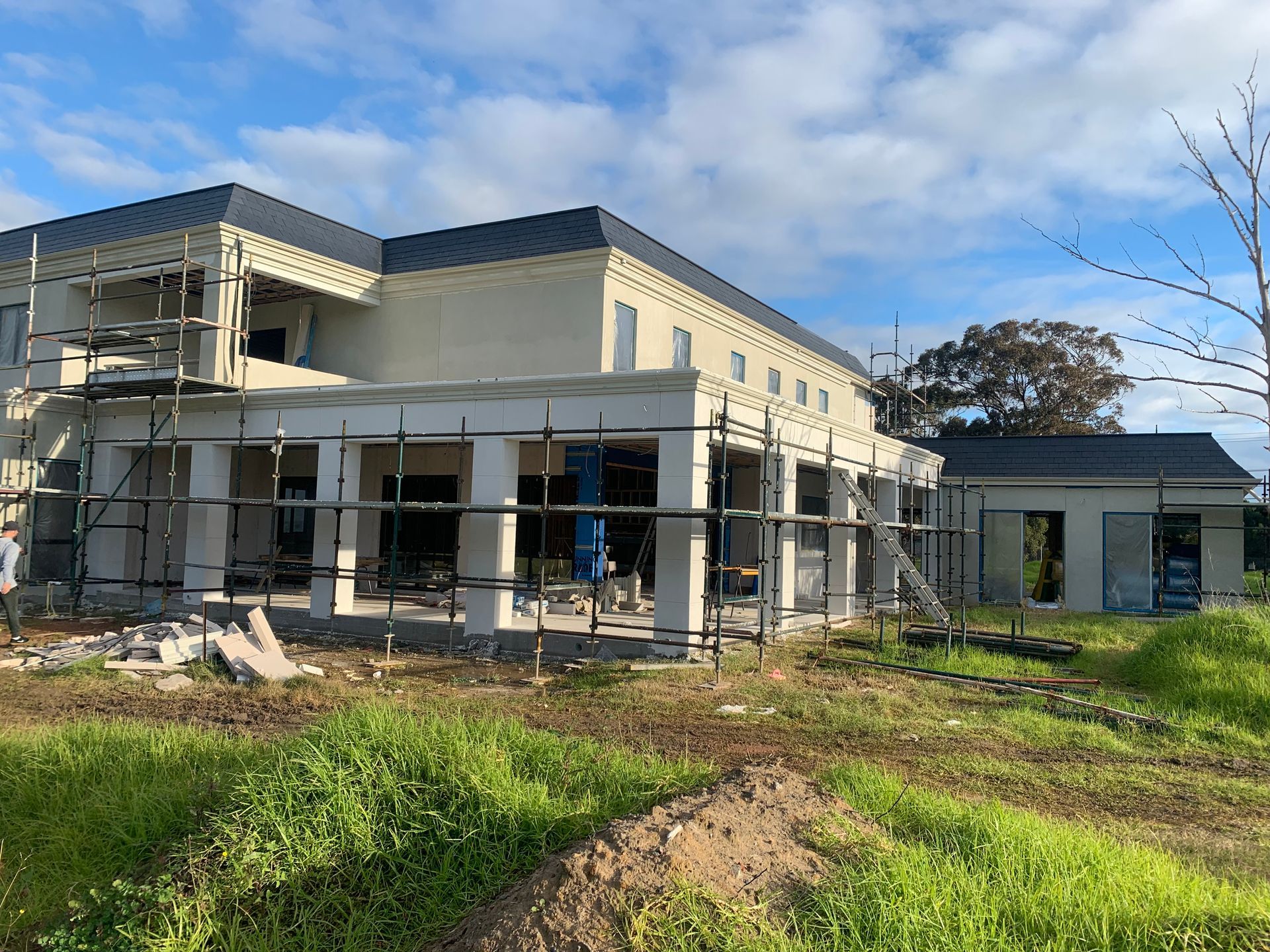 A large house is being built in the middle of a grassy field.