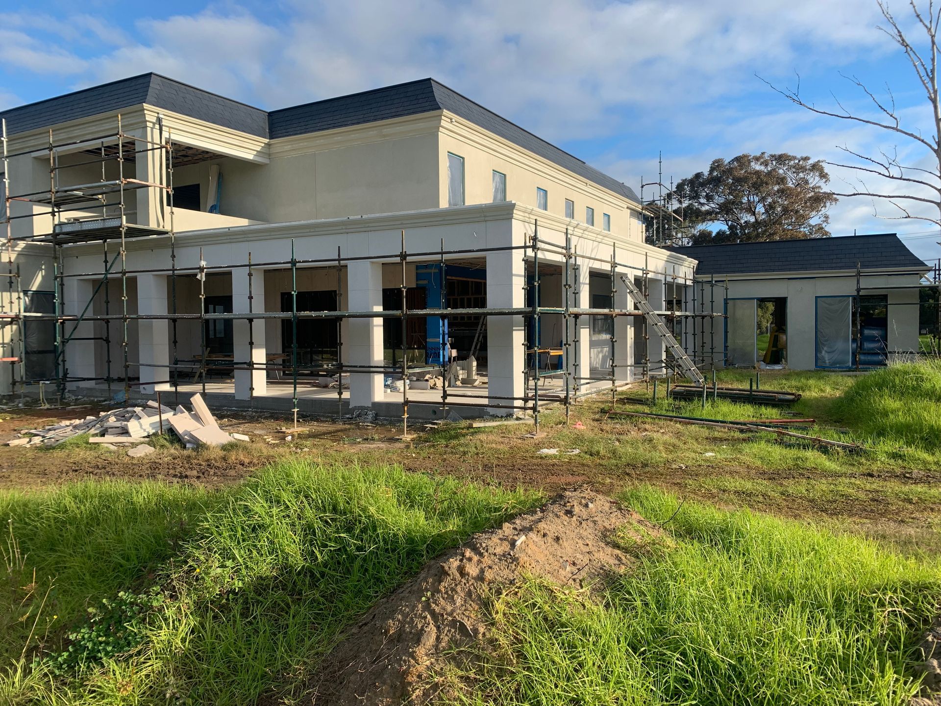 A large house is being built in the middle of a grassy field.