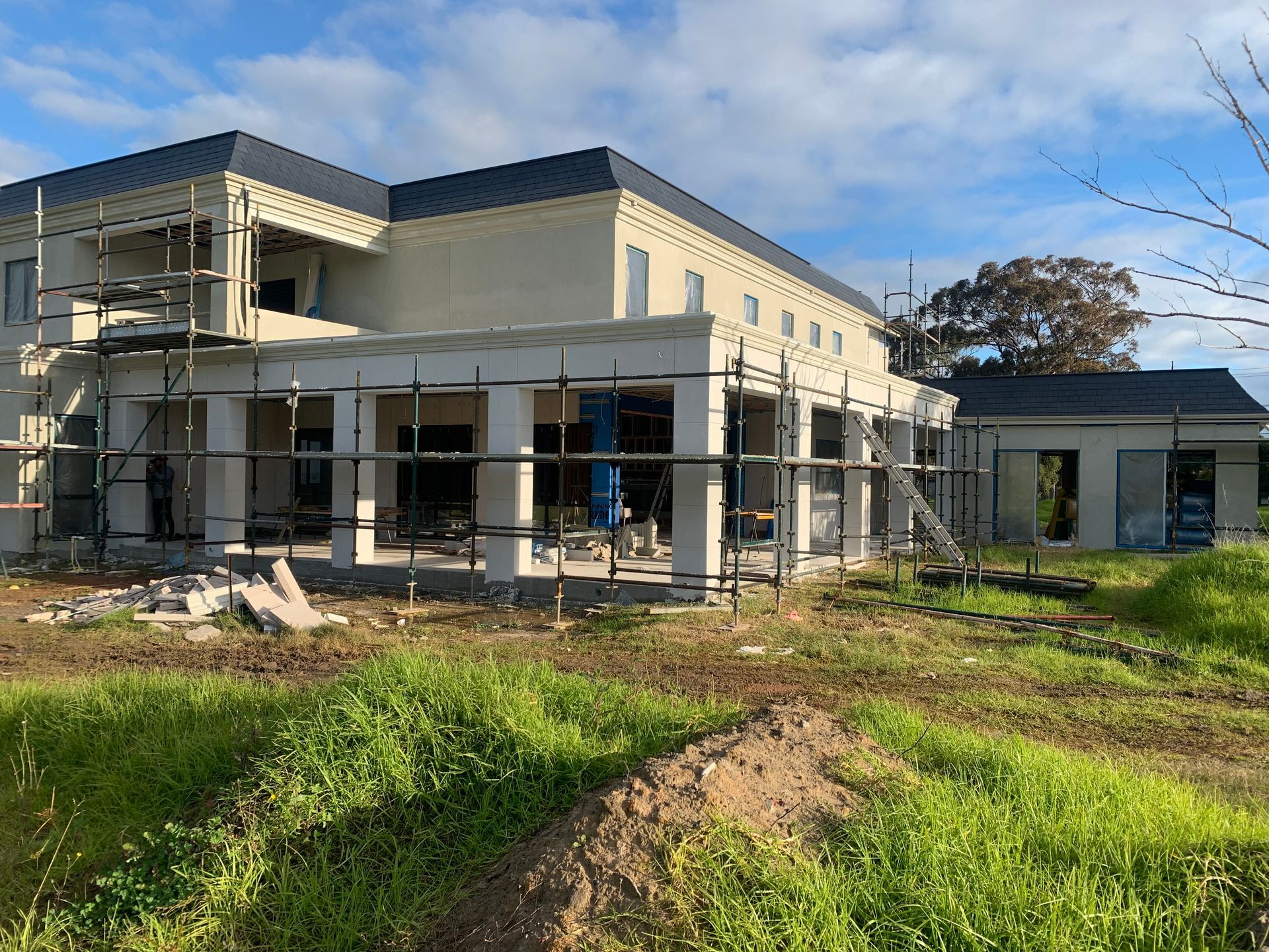 A large house is being built in a grassy field.