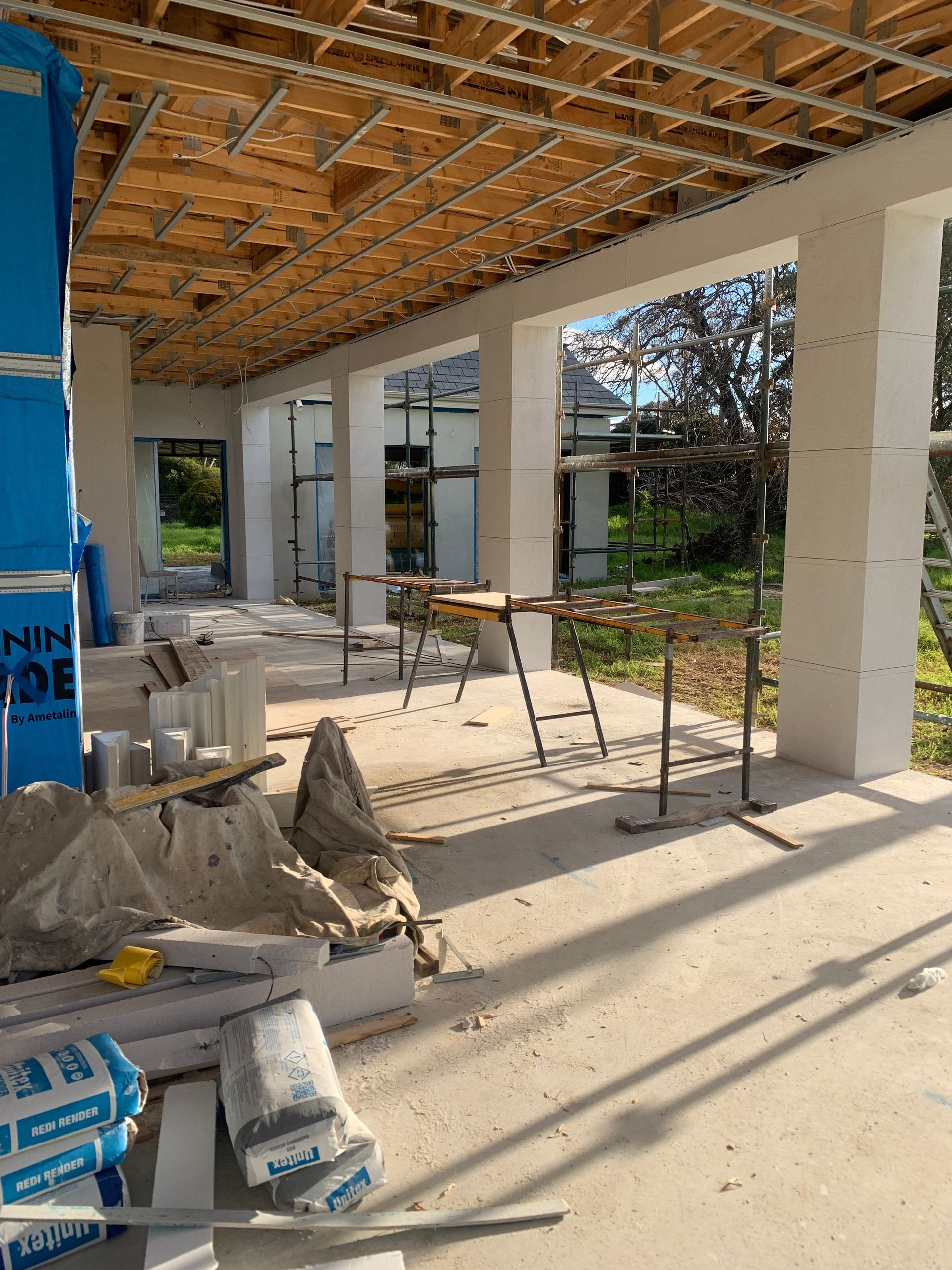 A building under construction with scaffolding and bags of cement.