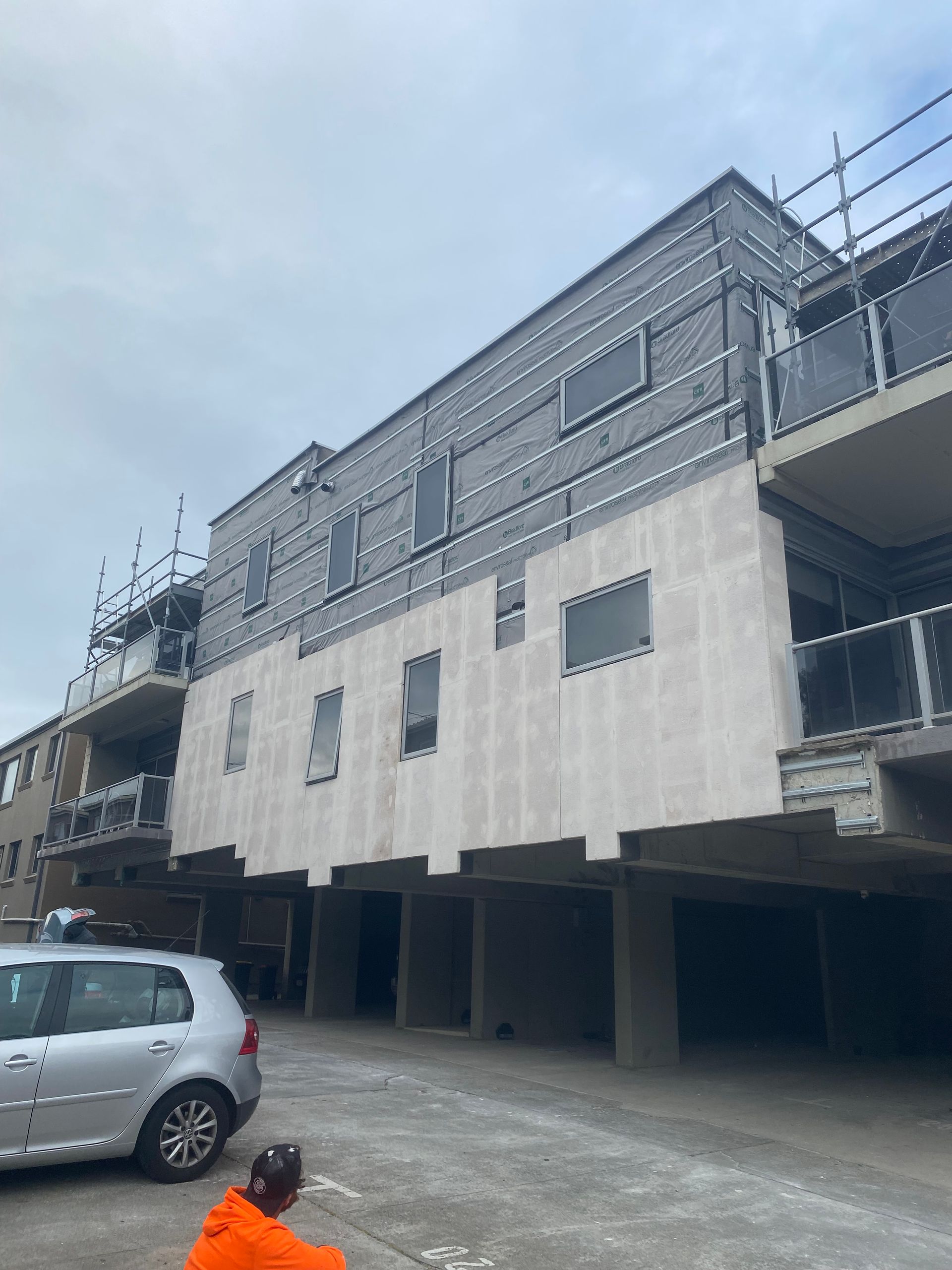 A car is parked in front of a building under construction