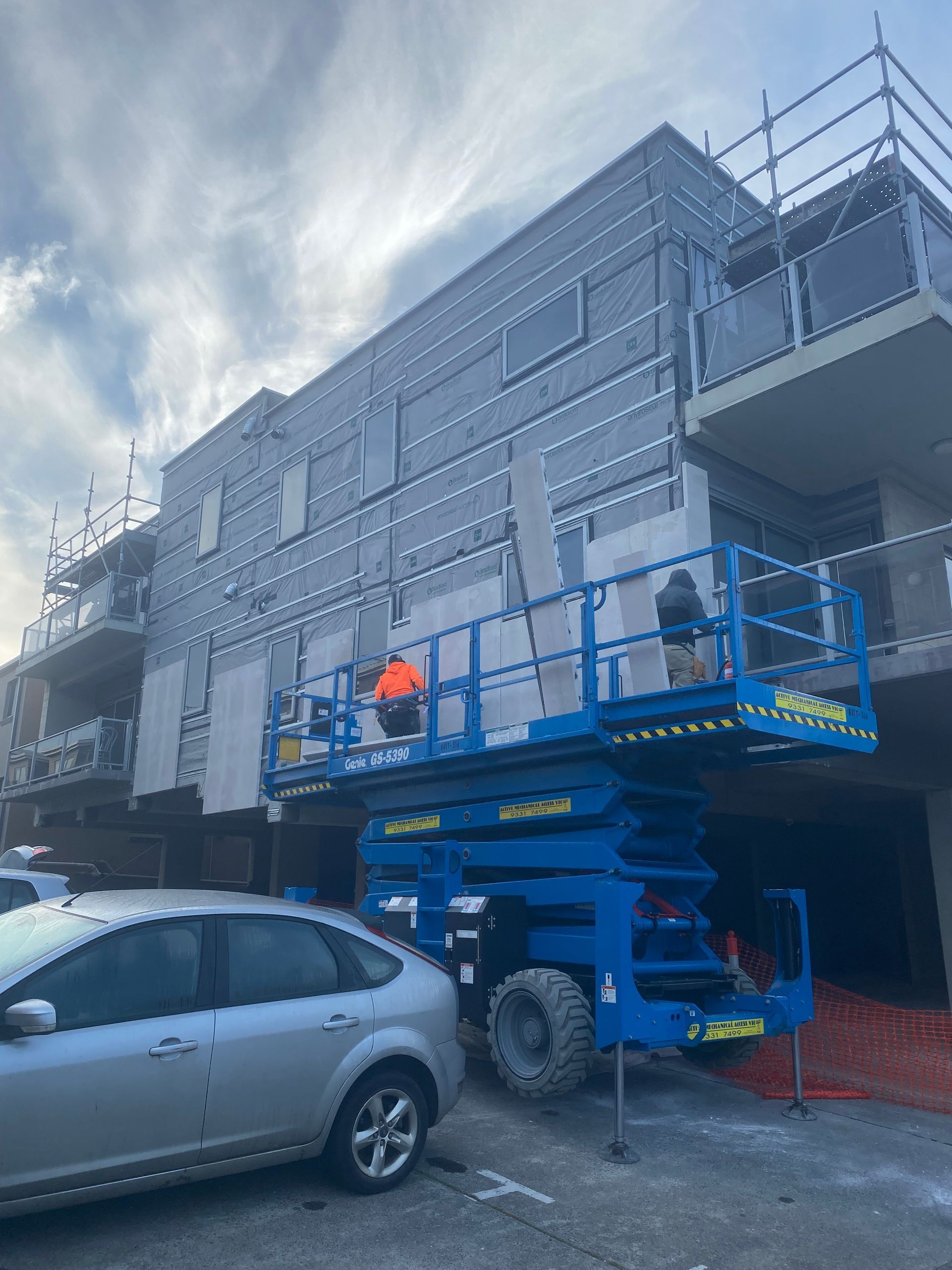 A car is parked in front of a building under construction
