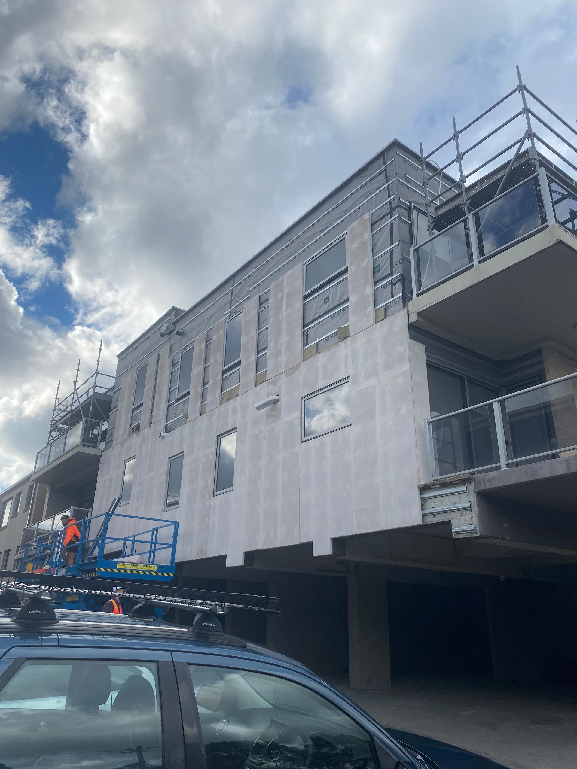 A car is parked in front of a building under construction