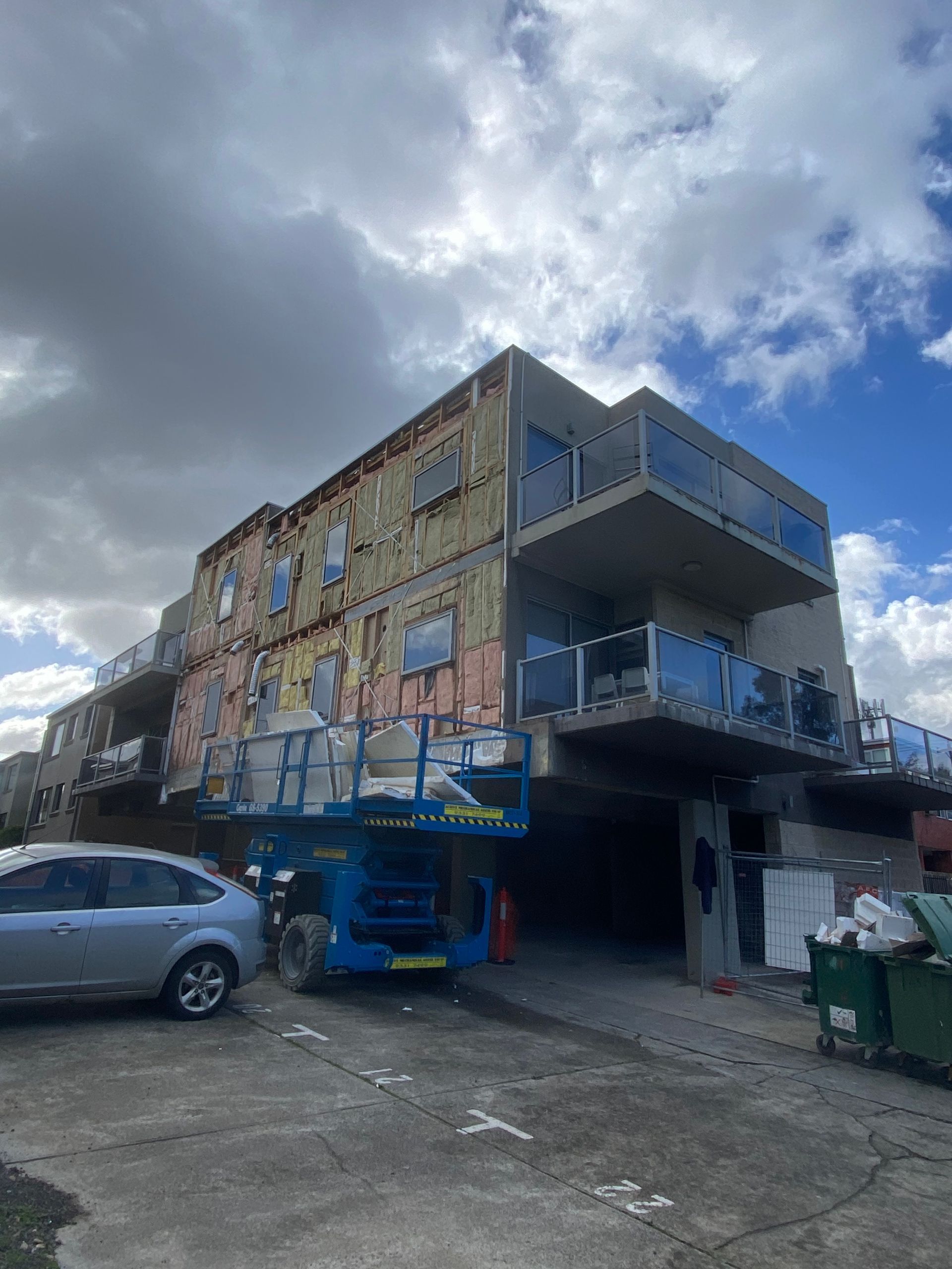 A building under construction with a car parked in front of it.