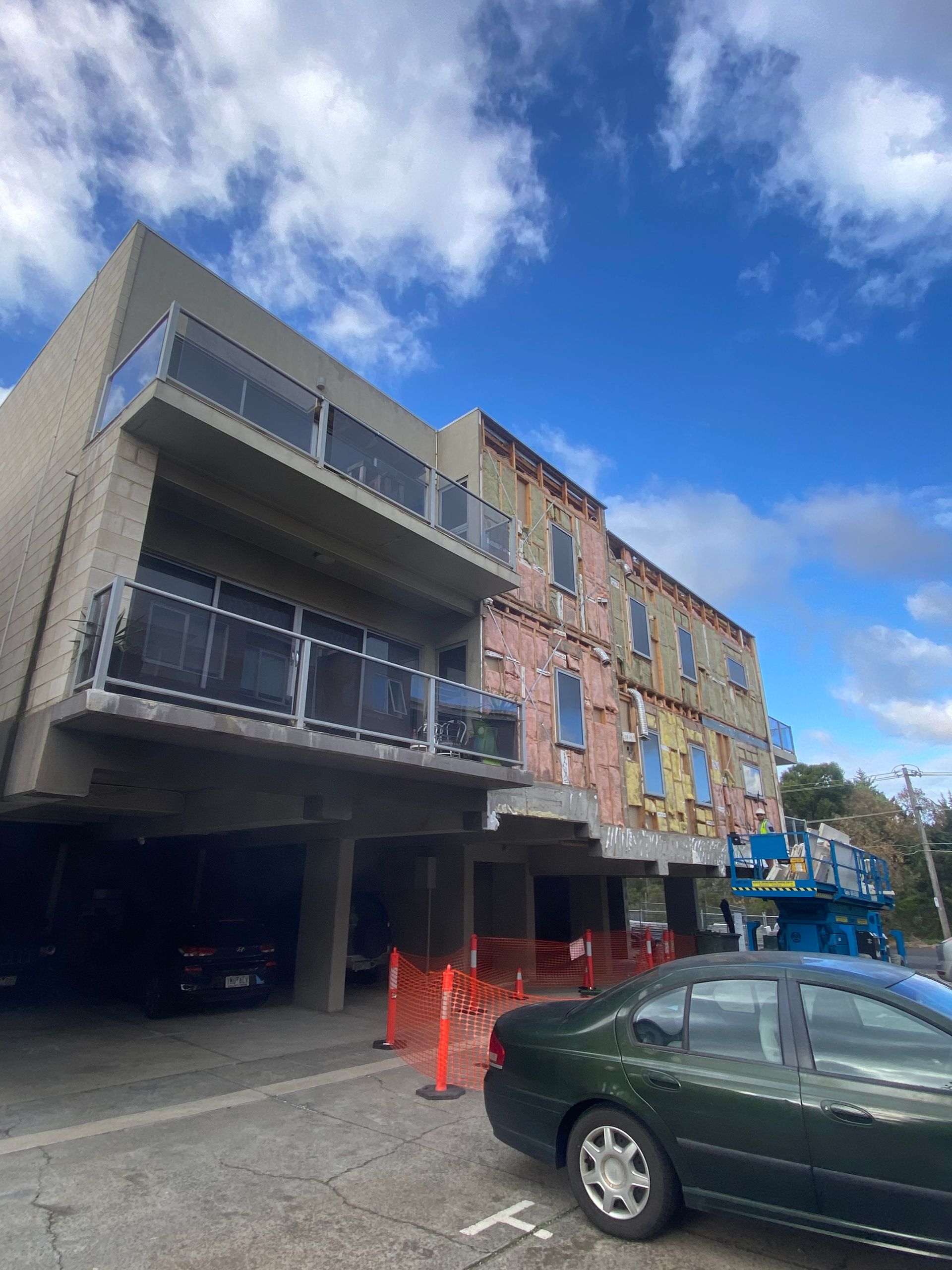 A car is parked in front of a building under construction