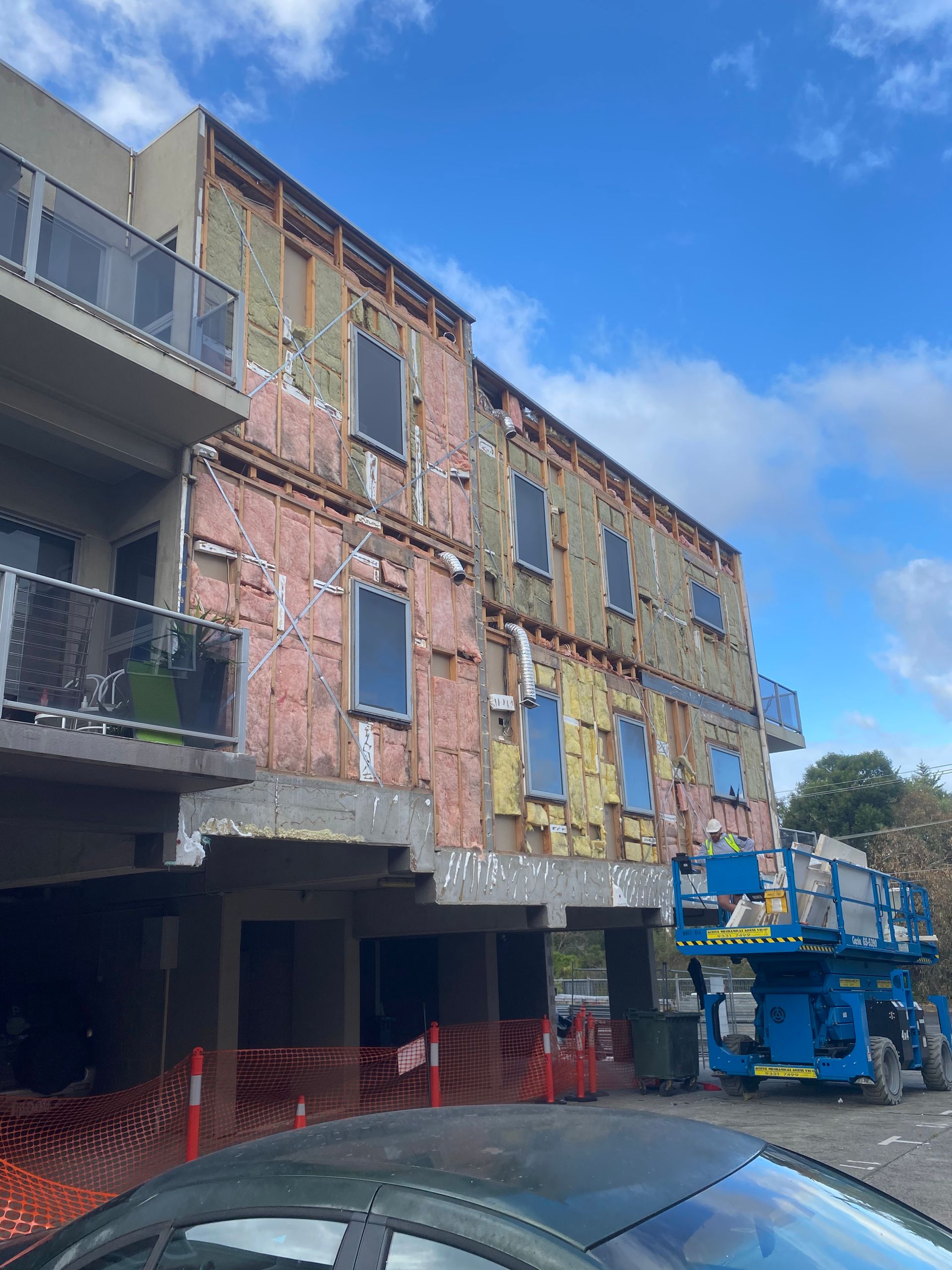 A car is parked in front of a building under construction