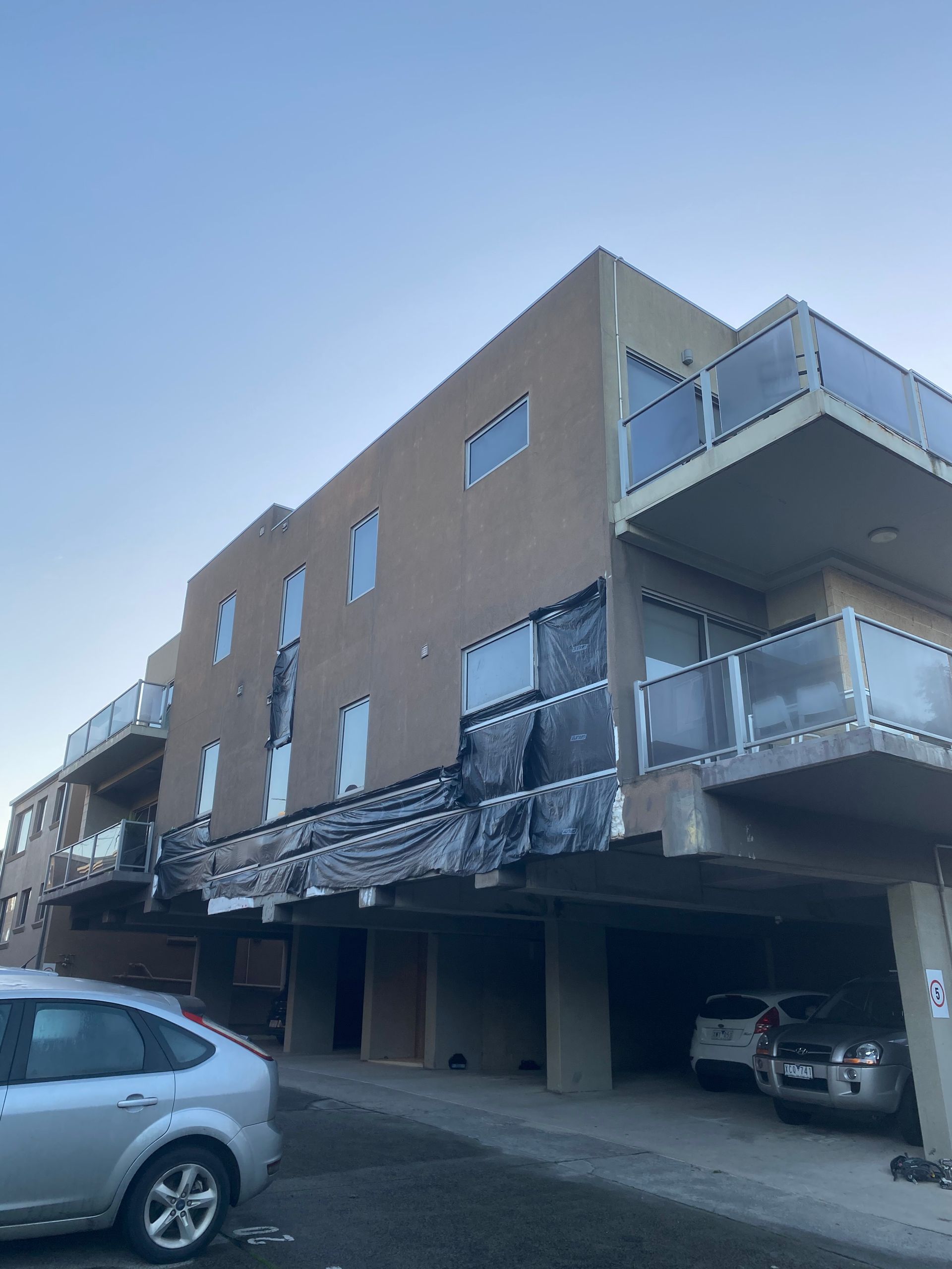 A car is parked in front of a building with balconies