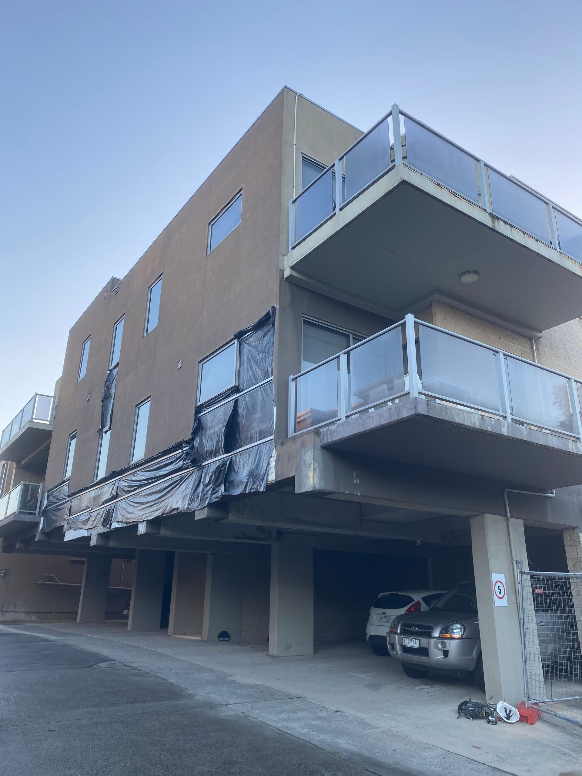 A building with a balcony and cars parked underneath it