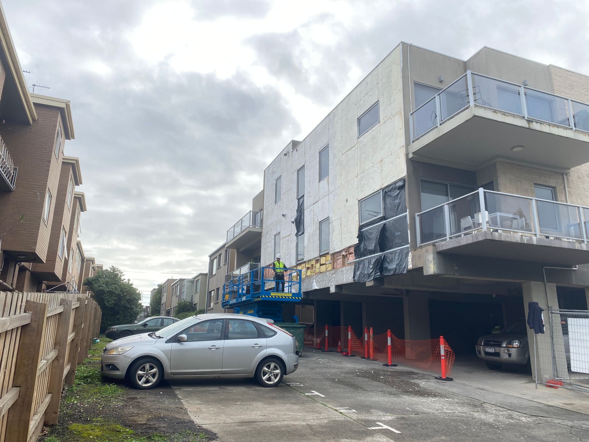 A car is parked in front of a building under construction.