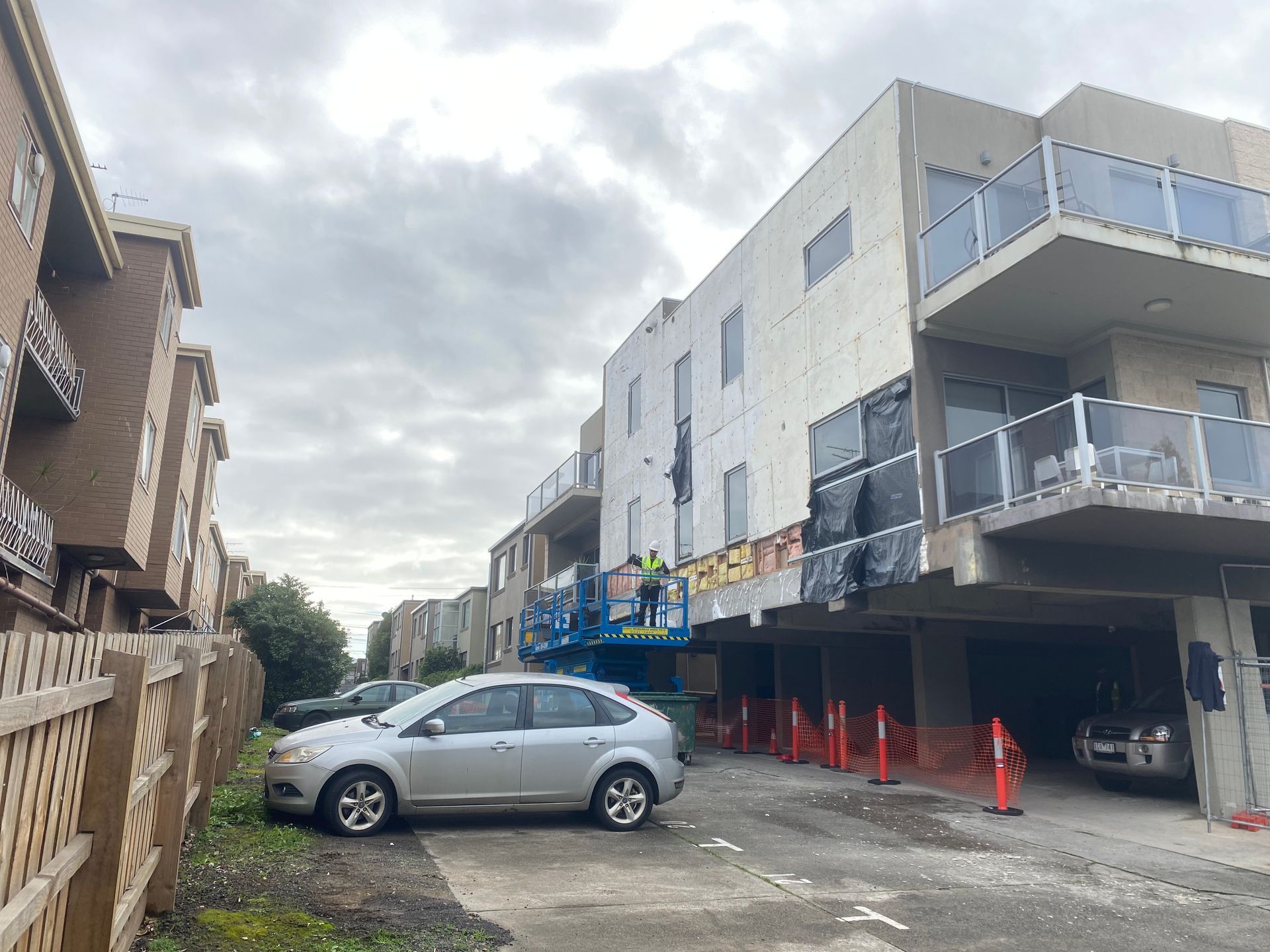 A car is parked in front of a building under construction.