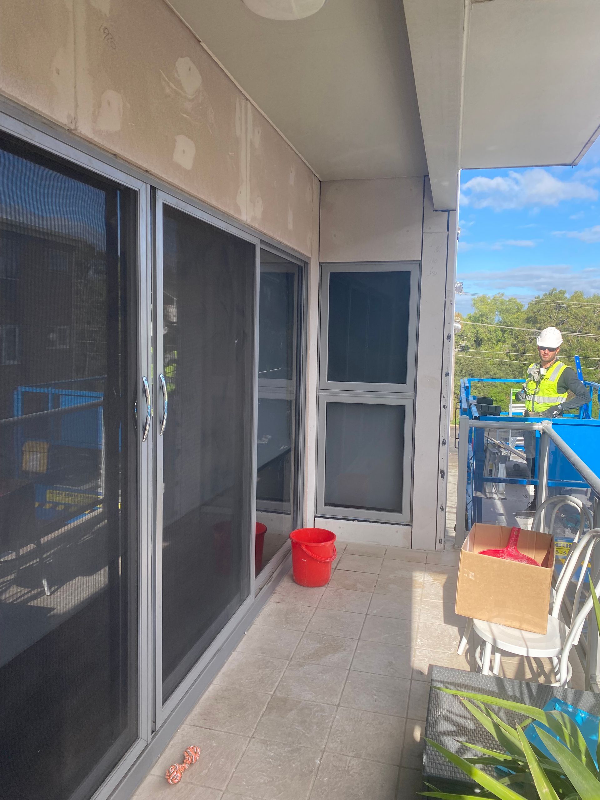 A balcony with sliding glass doors and a red bucket