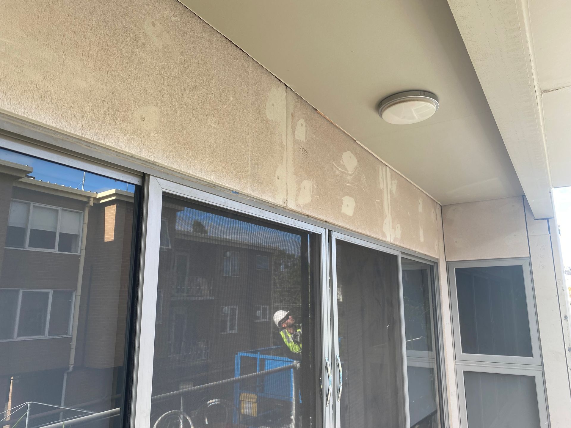 A balcony with sliding glass doors and a light on the ceiling.